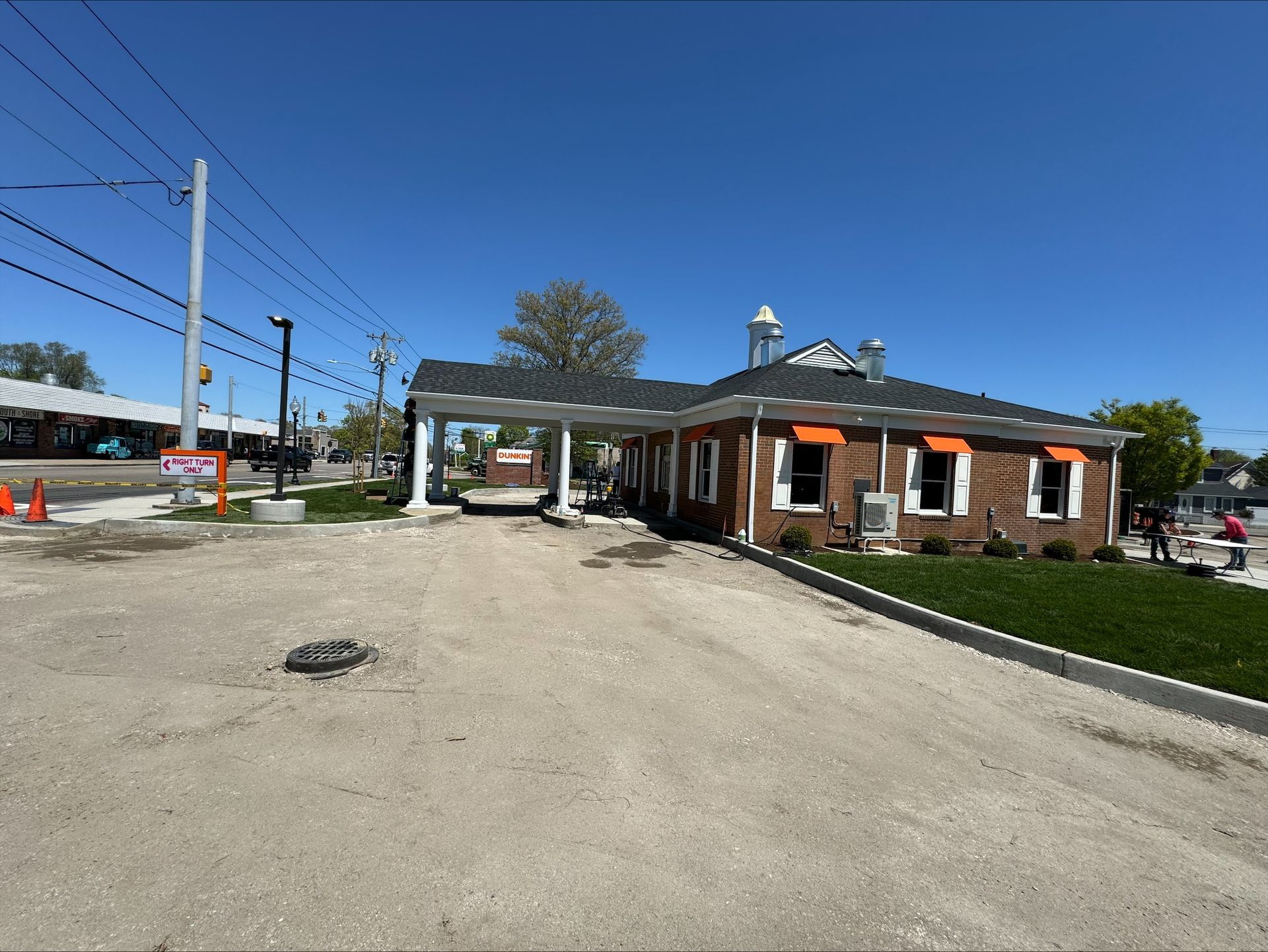 A brick building with a black roof is sitting on the side of a road.