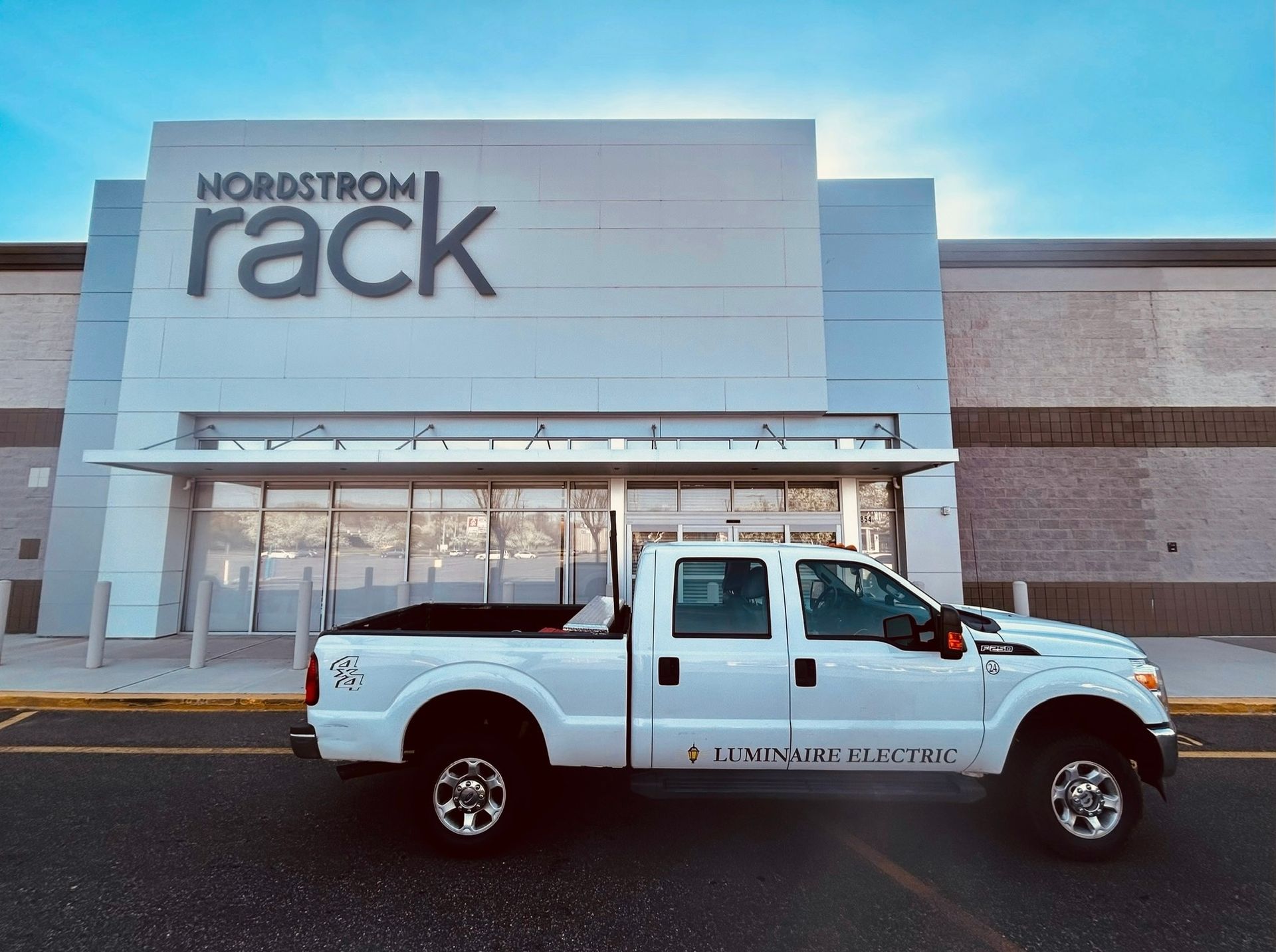 A white truck is parked in front of a Nordstrom Rack store