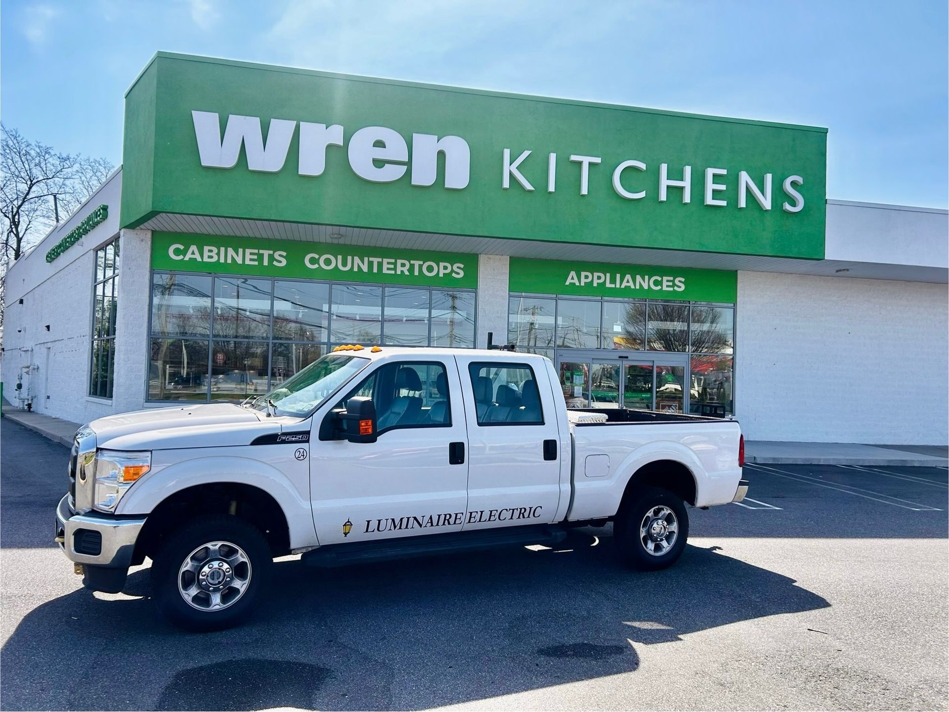 A white truck is parked in front of a Wren Kitchens store.