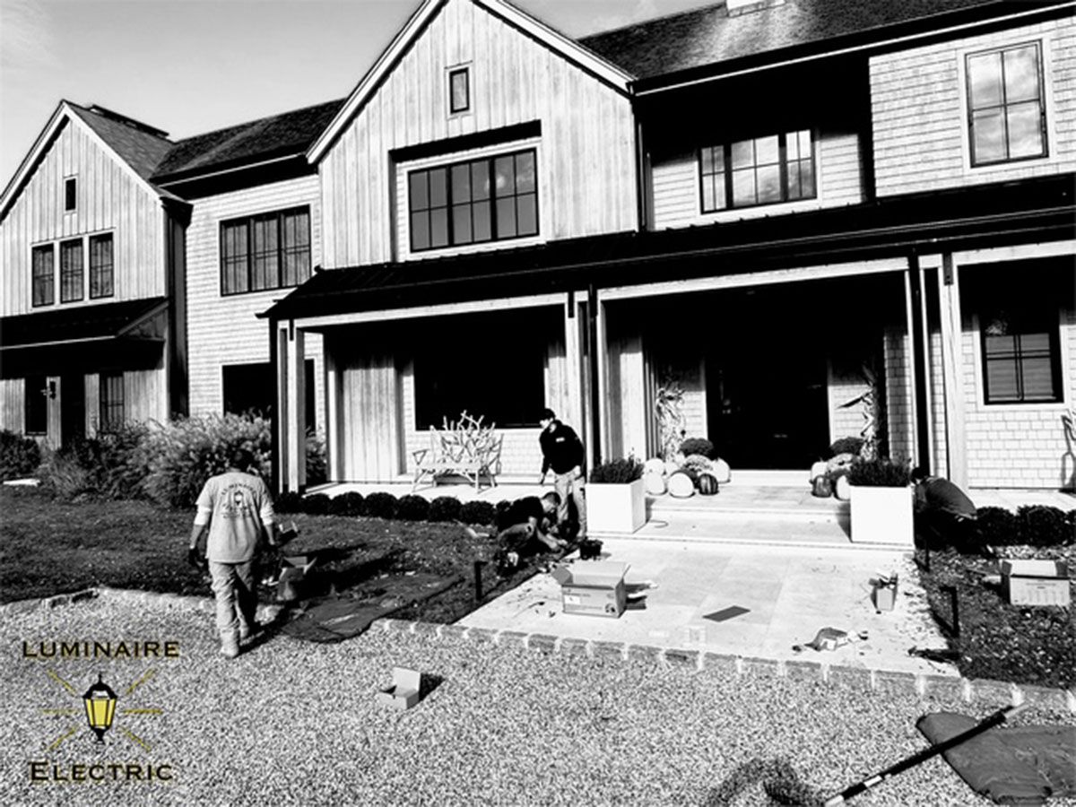 Electricians outside a two-story home with porch.