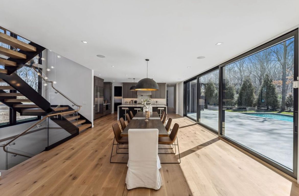 A large dining room with a table and chairs and a staircase