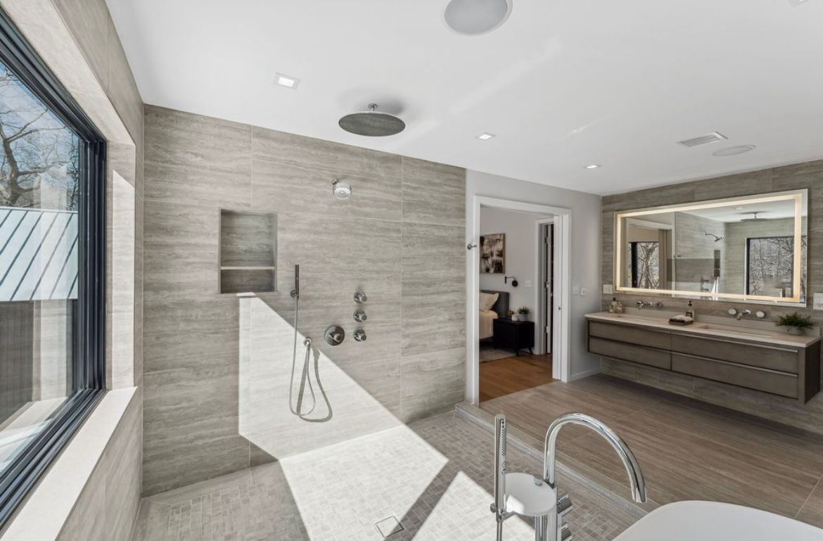 A bathroom with a tub, sink, shower and mirror