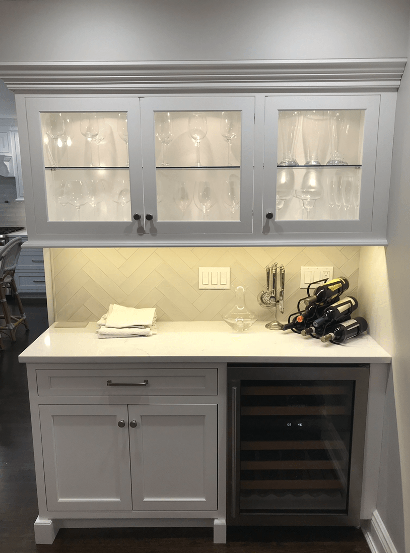 A kitchen with white cabinets and a wine cooler