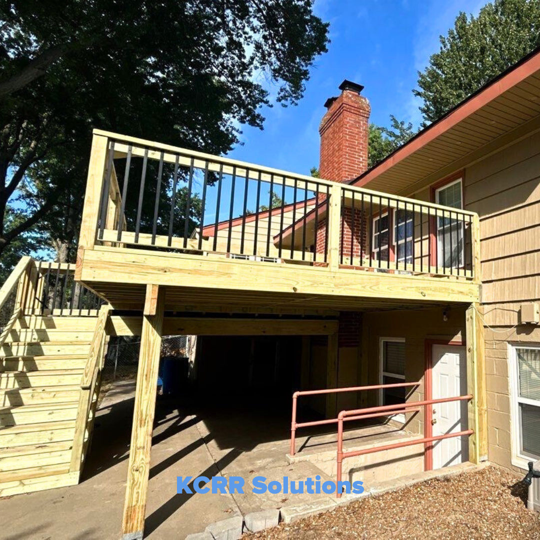 Photo of a newly rebuilt deck with wooden supports and black metal railings, following storm damage repairs. The roofline above the deck is also repaired, and the stairs provide safe access to the elevated deck area. The structure looks clean and modern, showcasing a successful reconstruction.