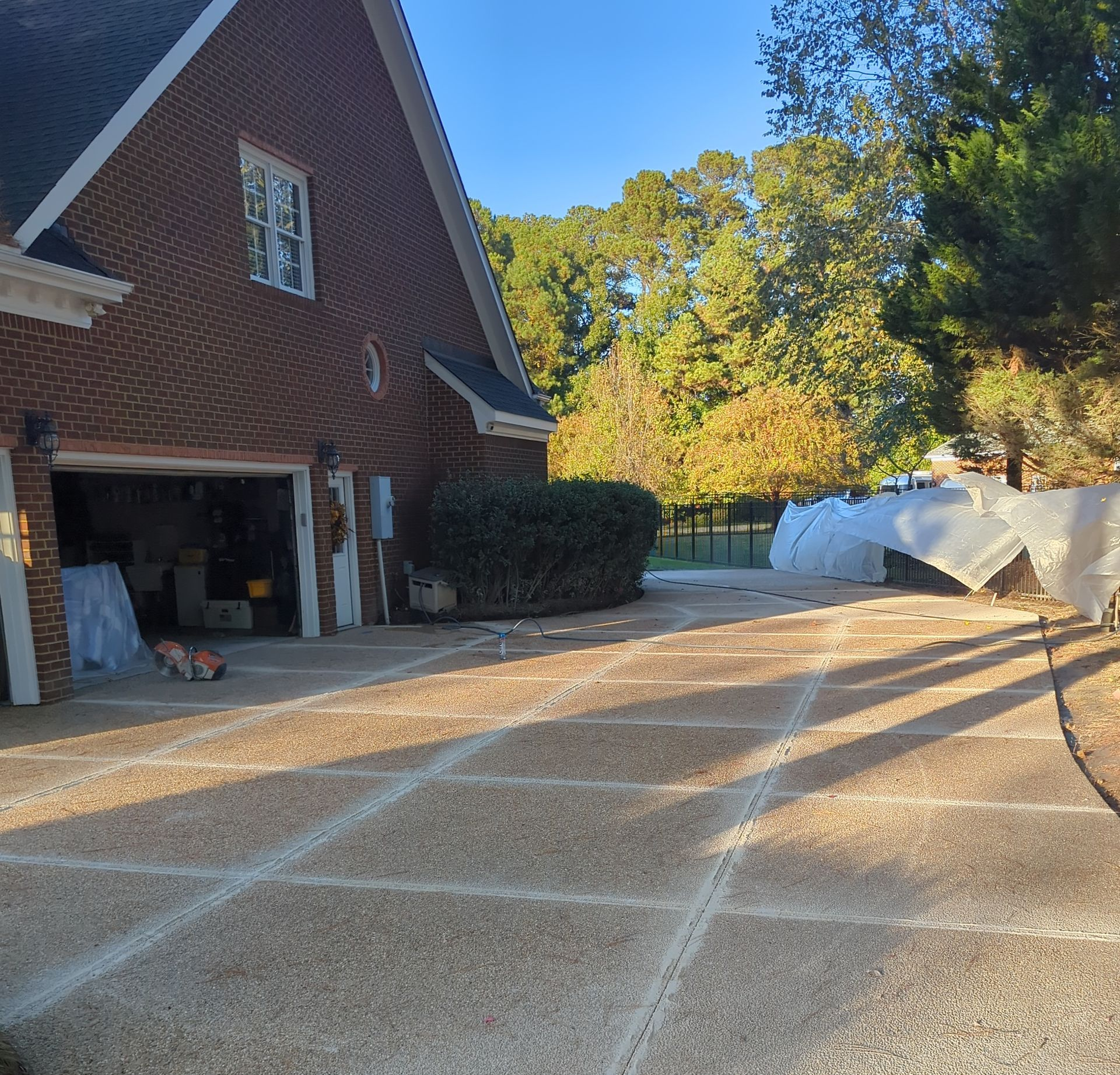 A brick house with an open garage and a driveway with a patterned pebble finish.