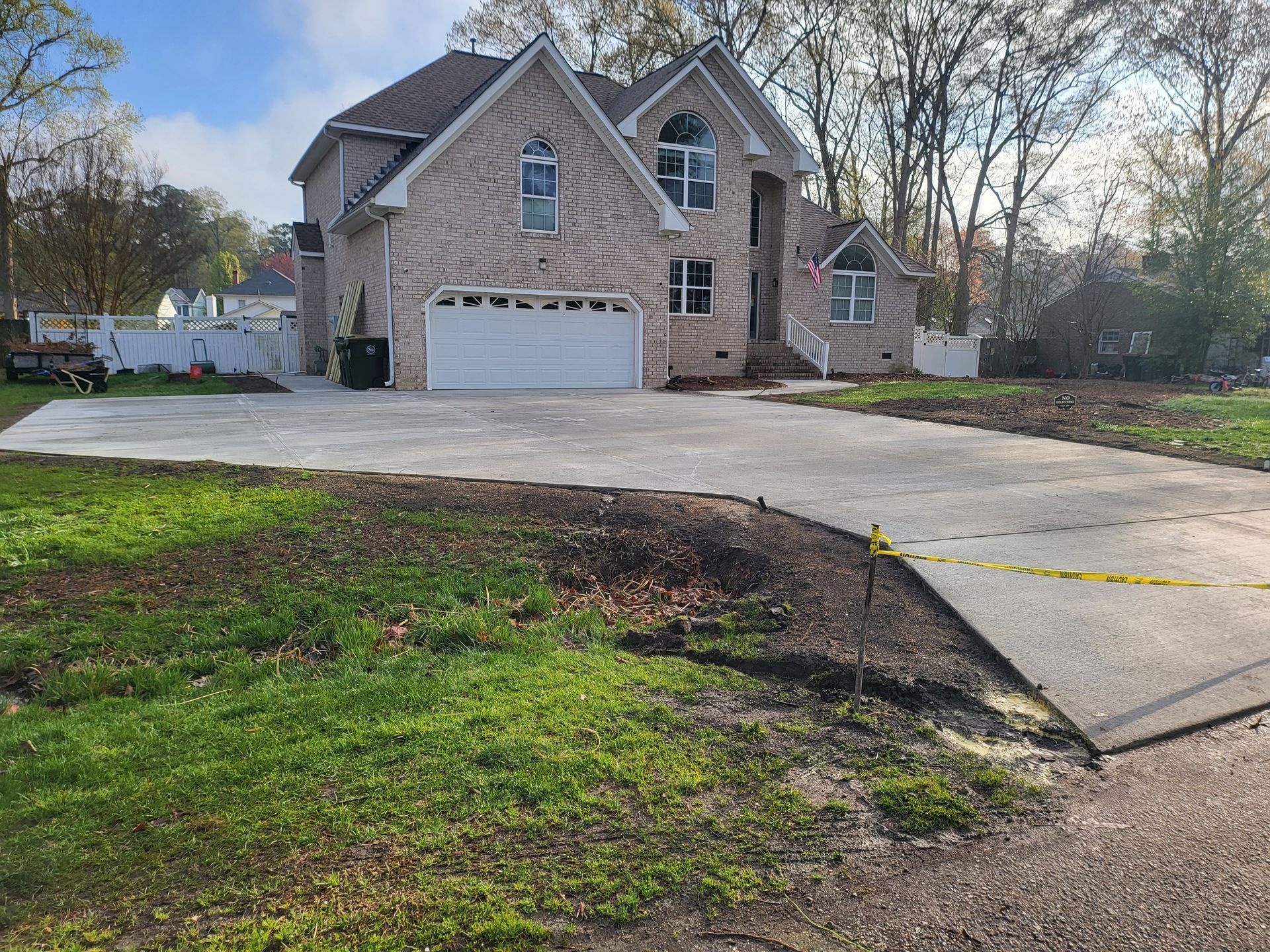 Two-story brick house with a newly poured concrete driveway and partially landscaped front yard.