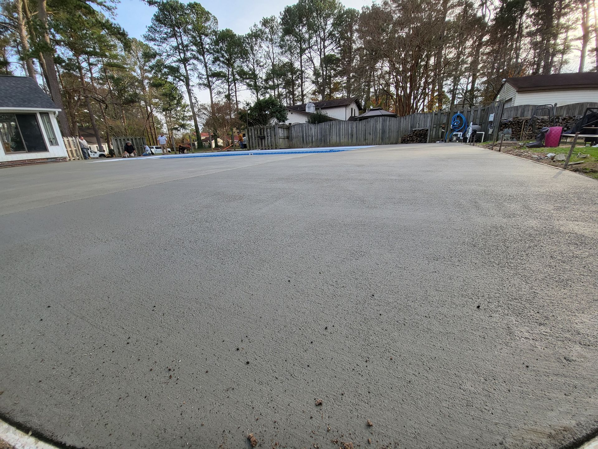 Large gray concrete slab in a yard, bordered by white, with trees and houses in the background.