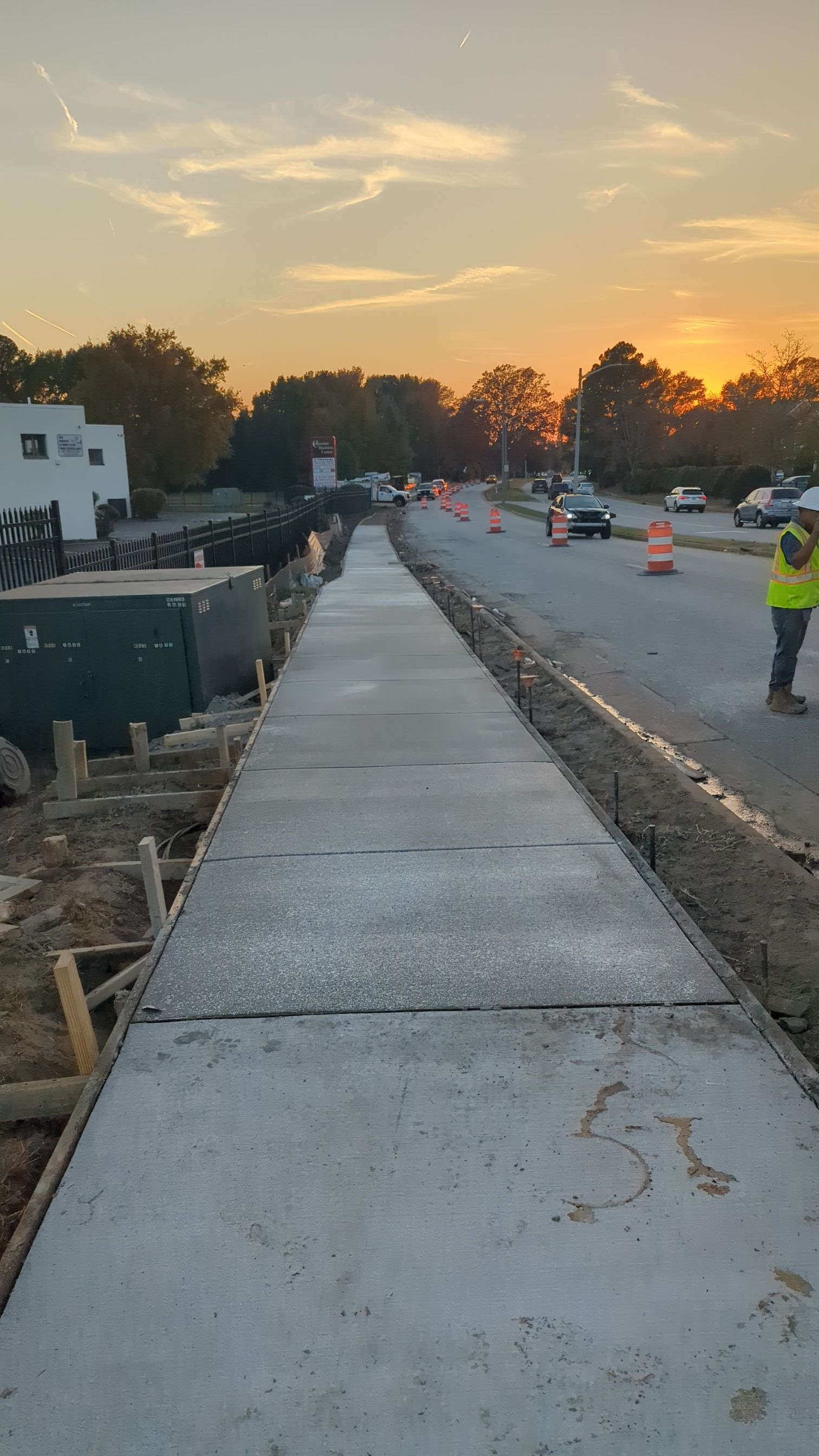 Newly poured concrete sidewalk construction site at sunset.