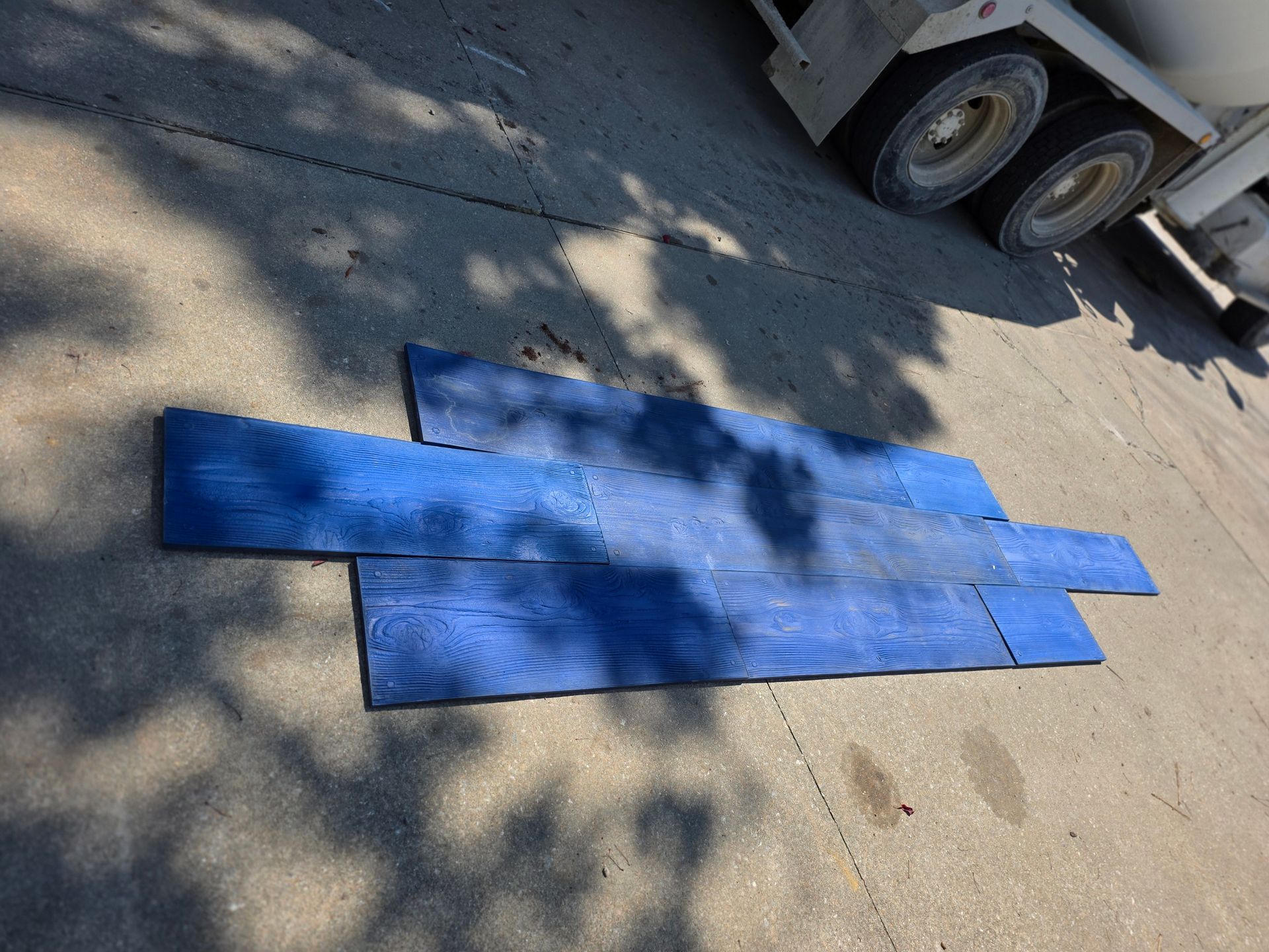 Blue textured concrete stamp on asphalt next to a cement truck.