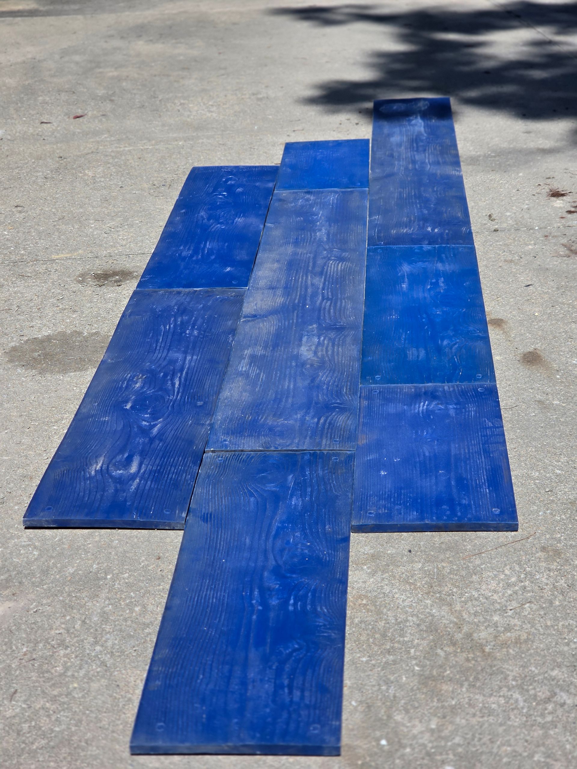 Blue rectangular concrete forms arranged on a gray surface, suggesting construction.