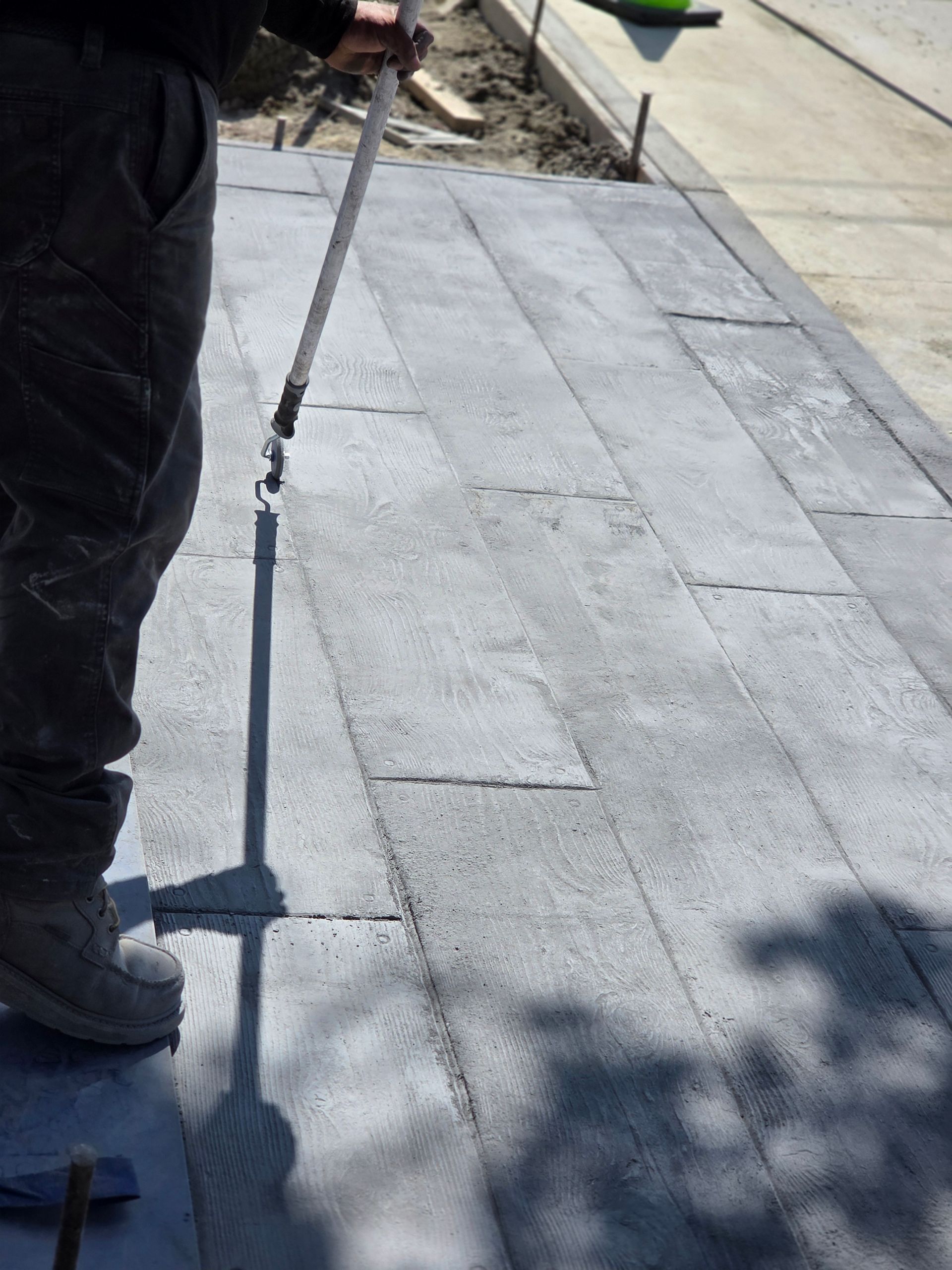 Person applying a coating to gray pavers on a walkway.