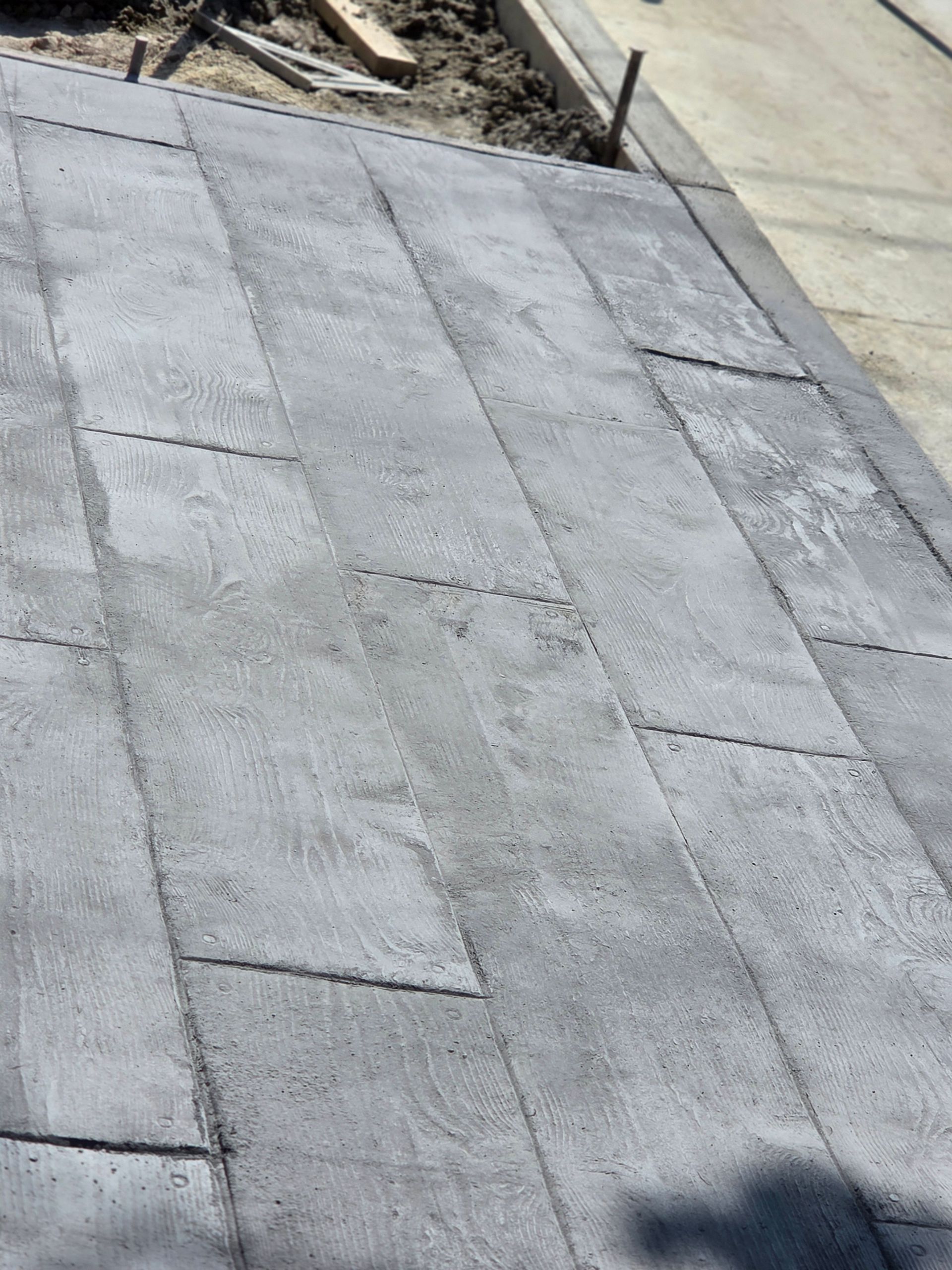 Gray concrete walkway with rectangular tile pattern.