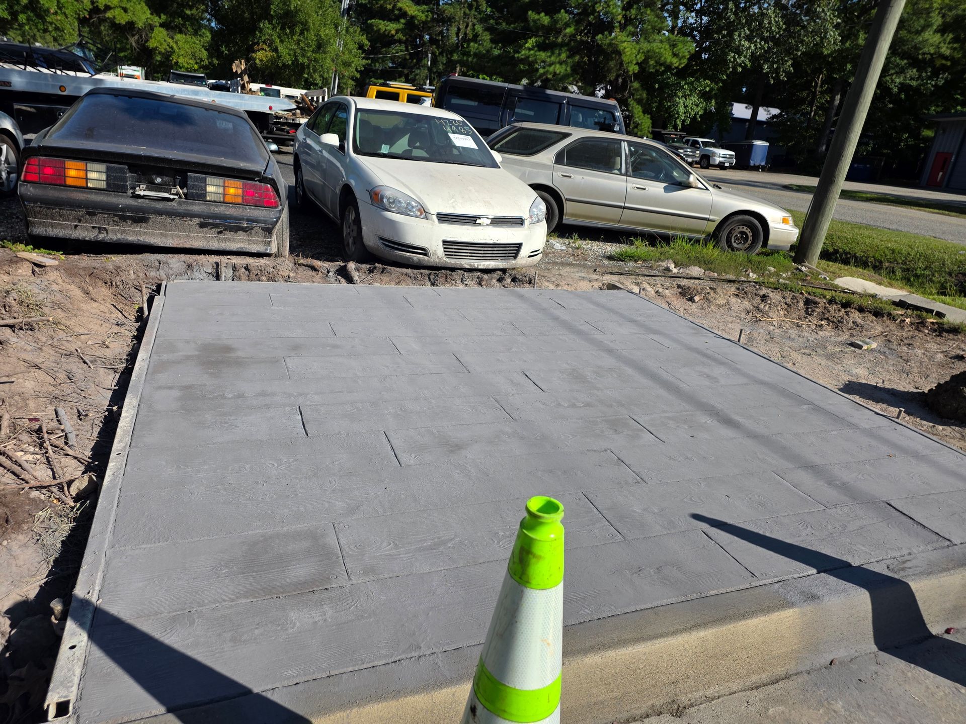 Concrete platform with parked cars behind it, next to a road, and a traffic cone.