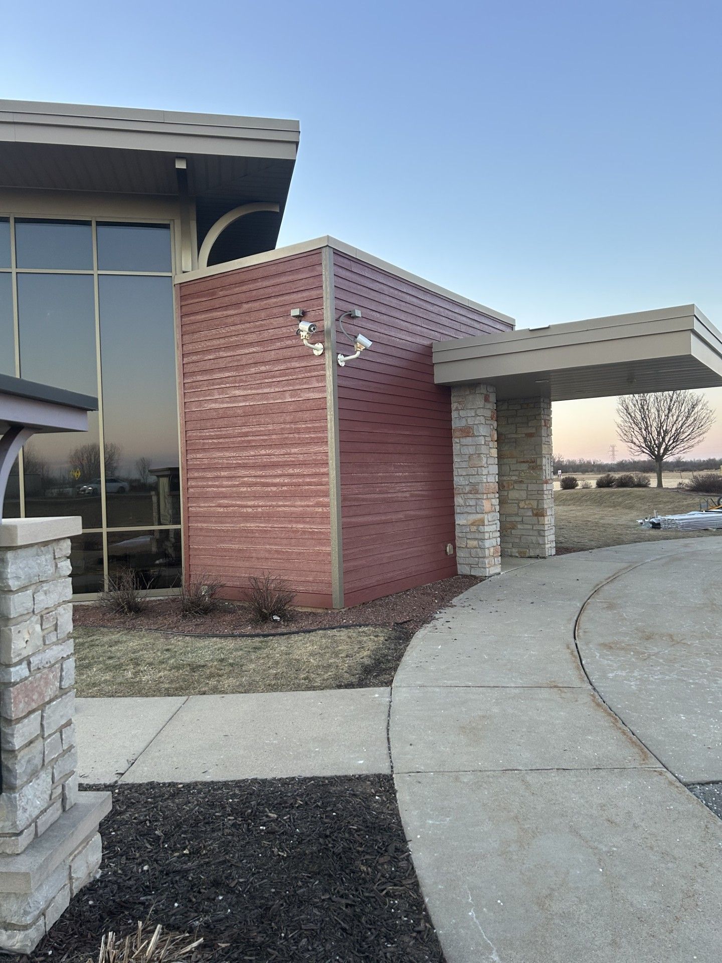 Exterior of a building with a brick facade and concrete pathway. A clear blue sky is above.