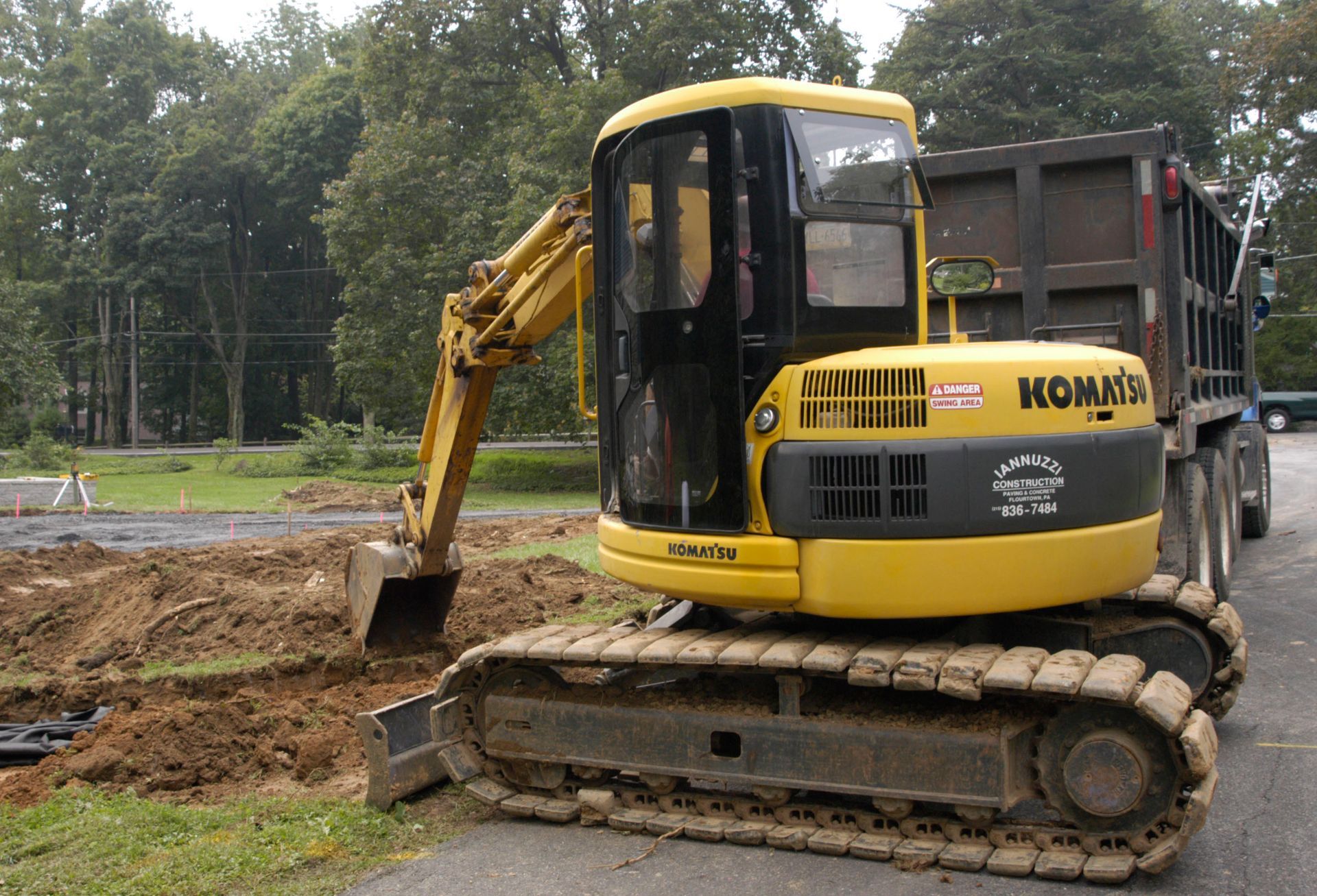 Yellow Komatsu excavator digging earth next to a dump truck in a construction site.