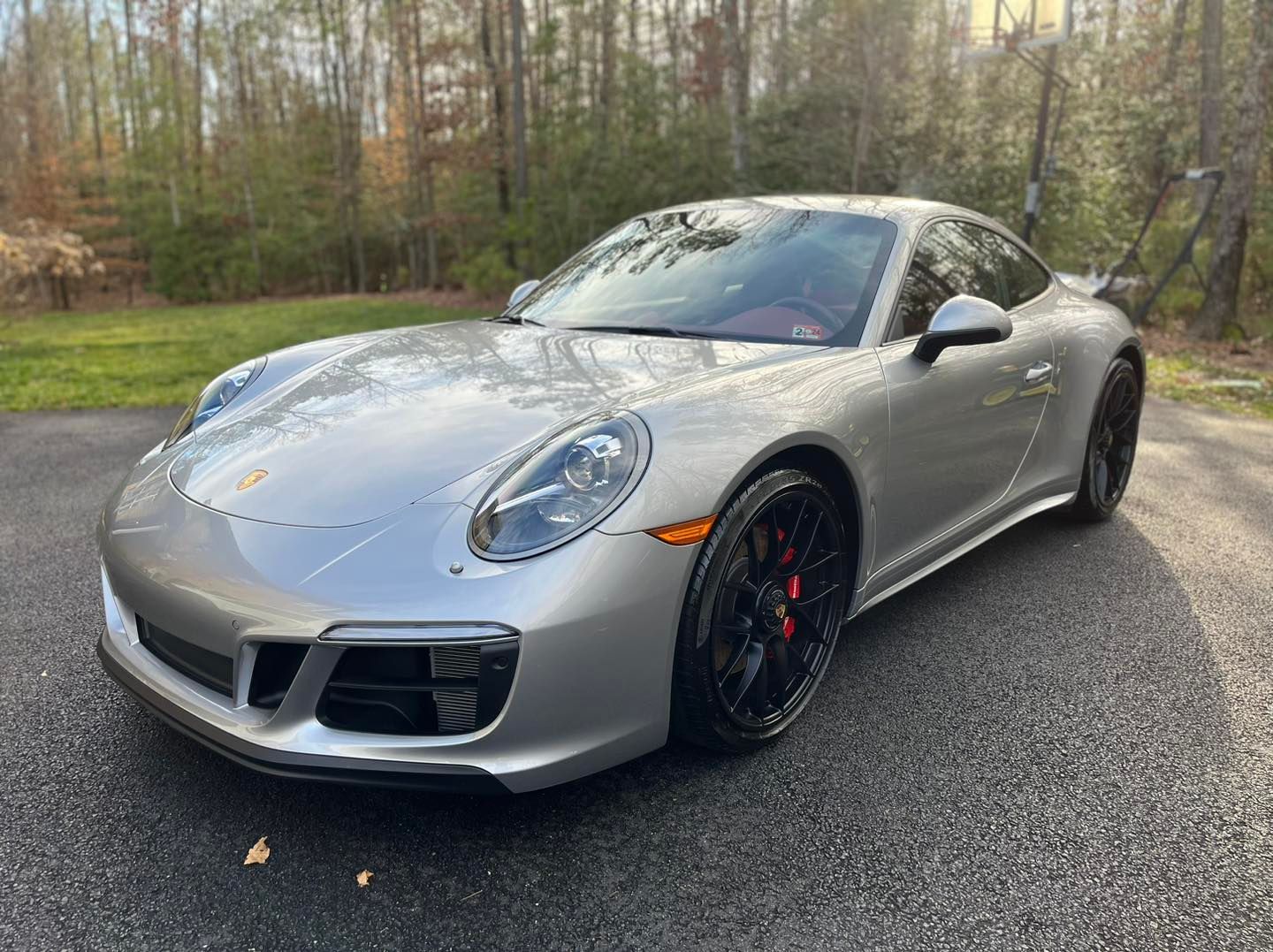 A silver porsche 911 gts is parked on the side of a road.