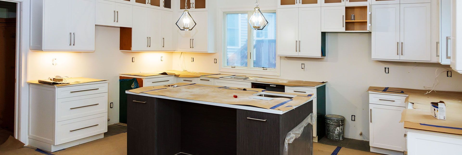 A kitchen under construction with white cabinets and a large island