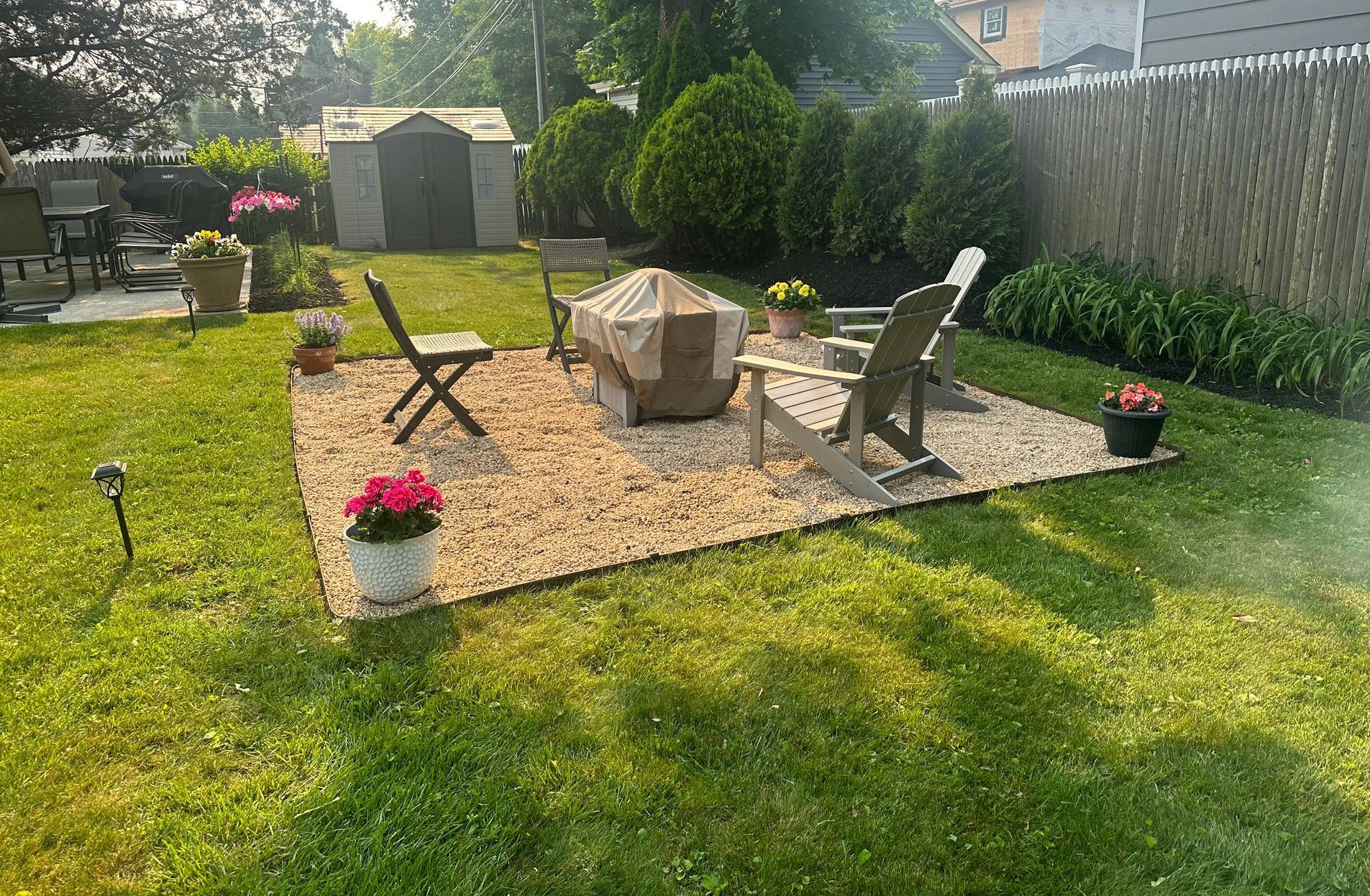 a couple chairs around a firepit and flowers