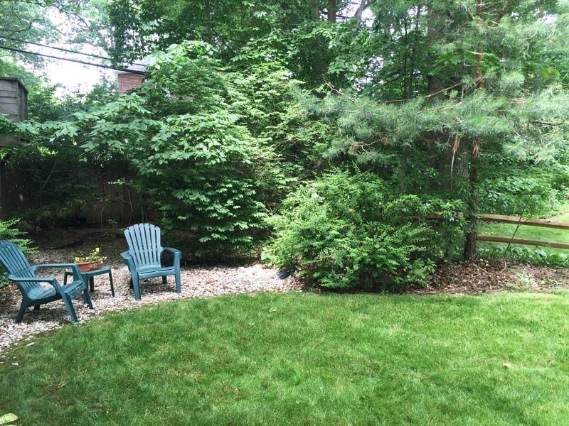 A backyard with two blue chairs and a table