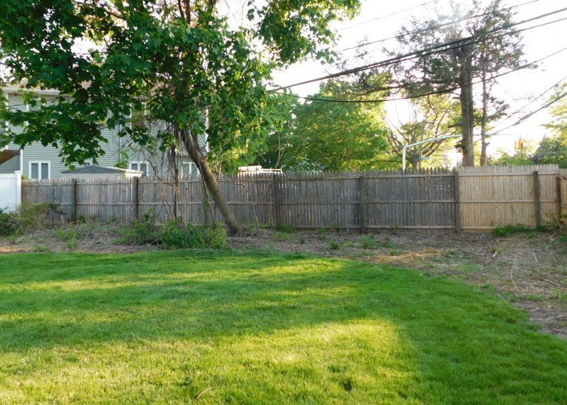 A backyard with a wooden fence and a lush green lawn