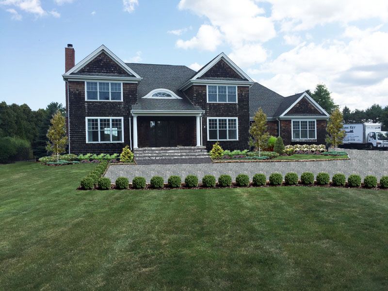 After photo of a large house with a lush green lawn in front of it