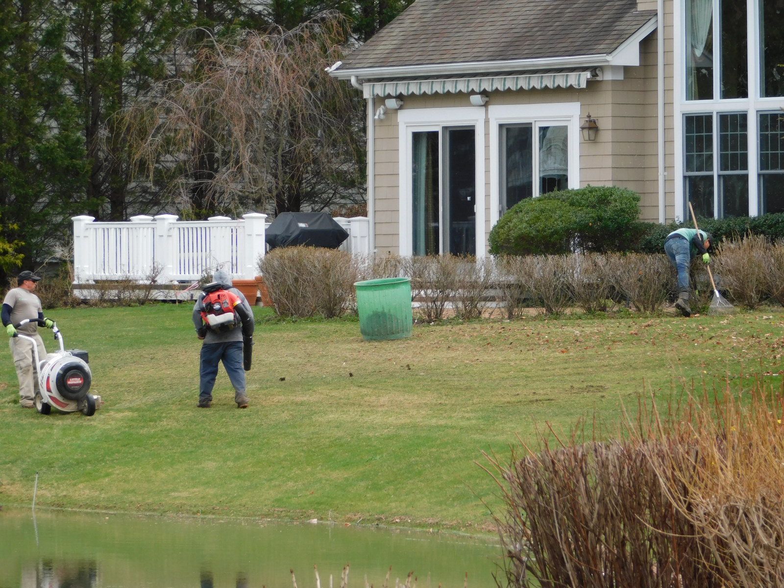 Two men are standing in a grassy yard in front of a house