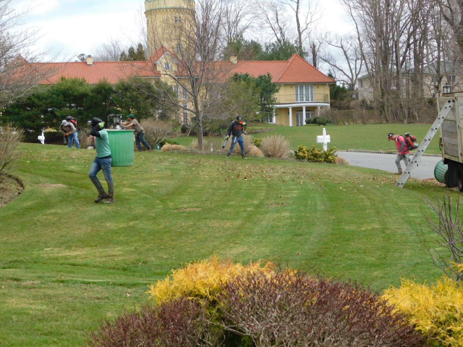 A group of people are standing in a grassy field in front of a house