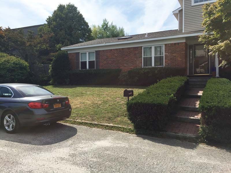 A car is parked in front of a brick house