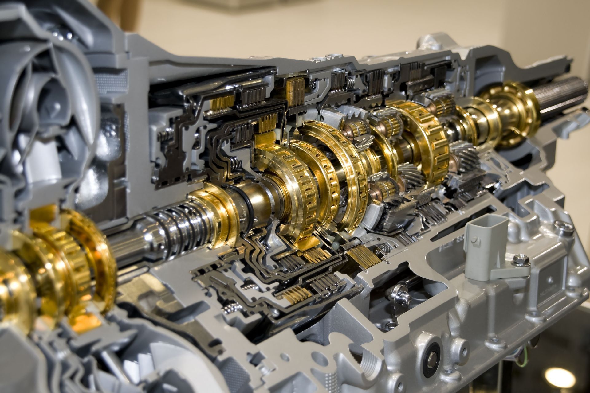 Cutaway view of a car transmission with shiny gold gears and metal components exposed