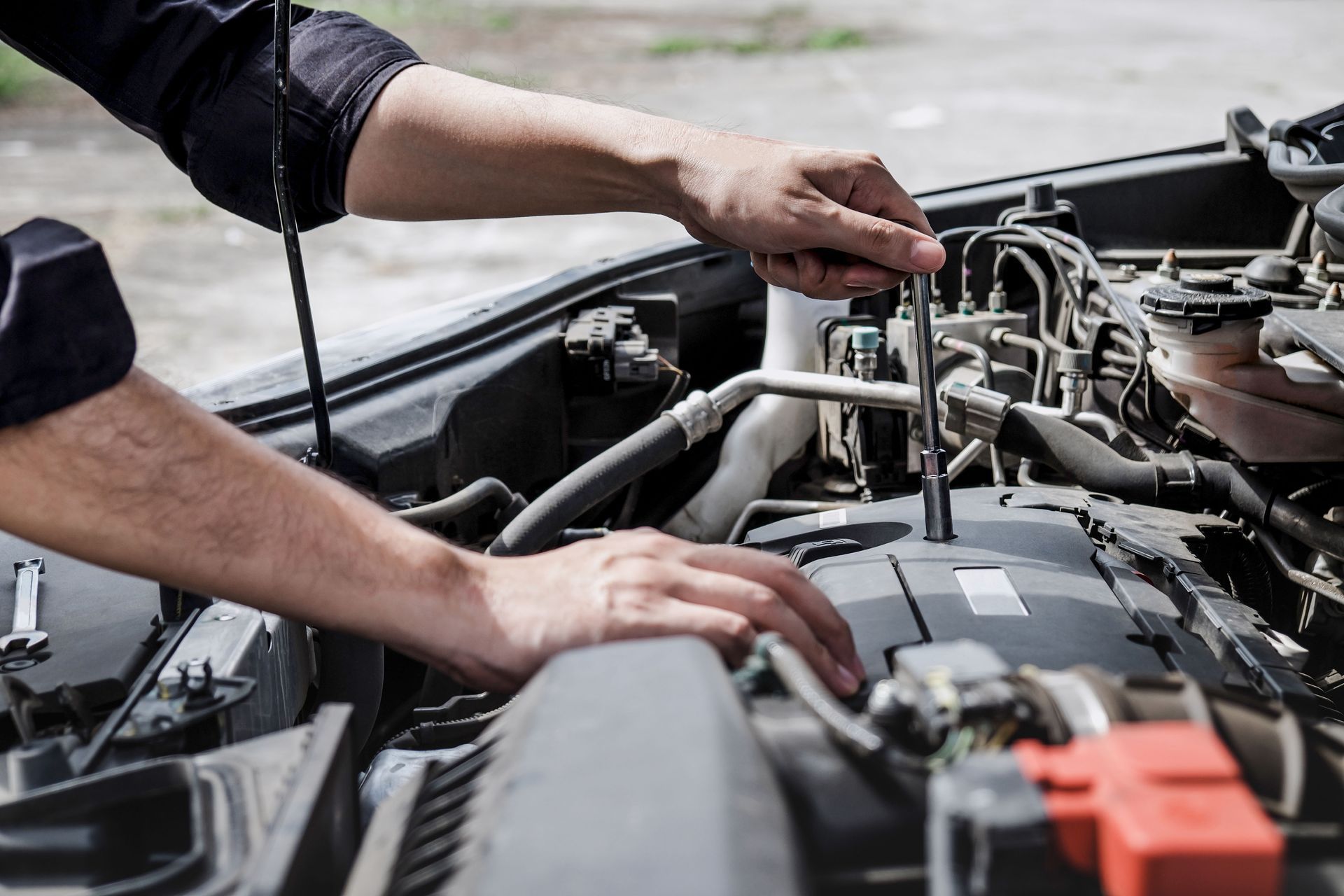 Mechanic inspecting a car engine with hands on hoses and components under the open hood