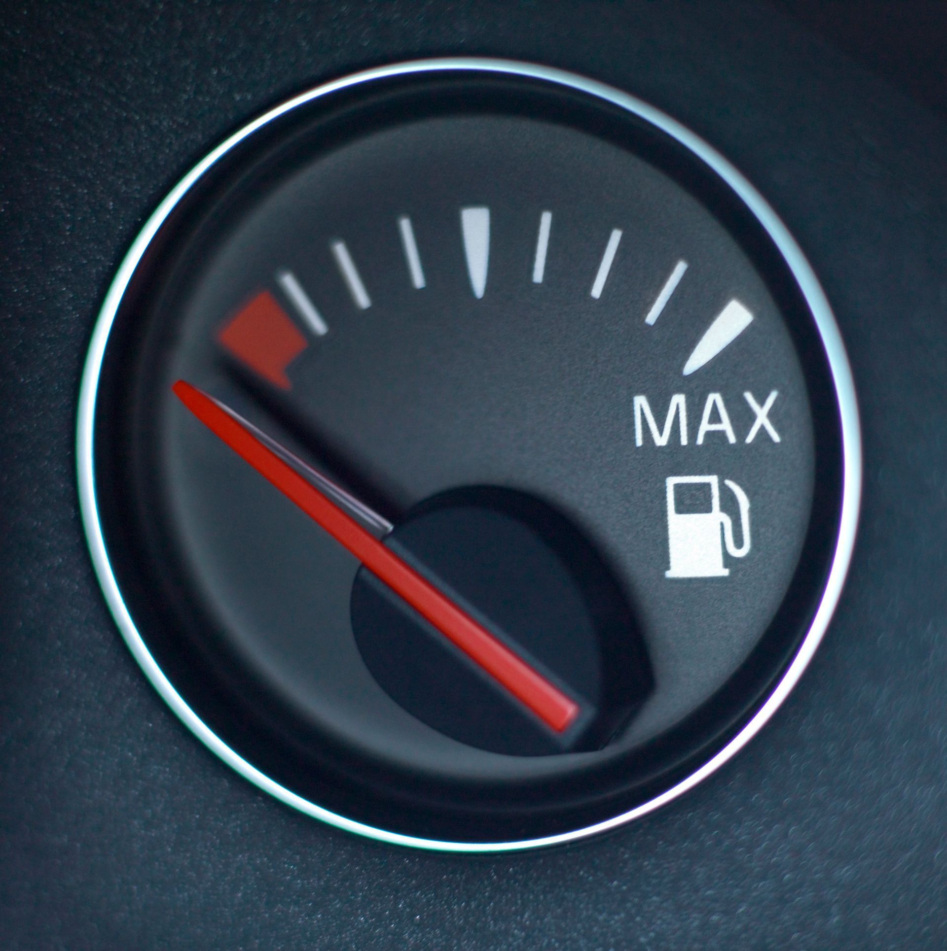 Car fuel gauge near empty, red needle in the lower range with MAX label and gas pump icon