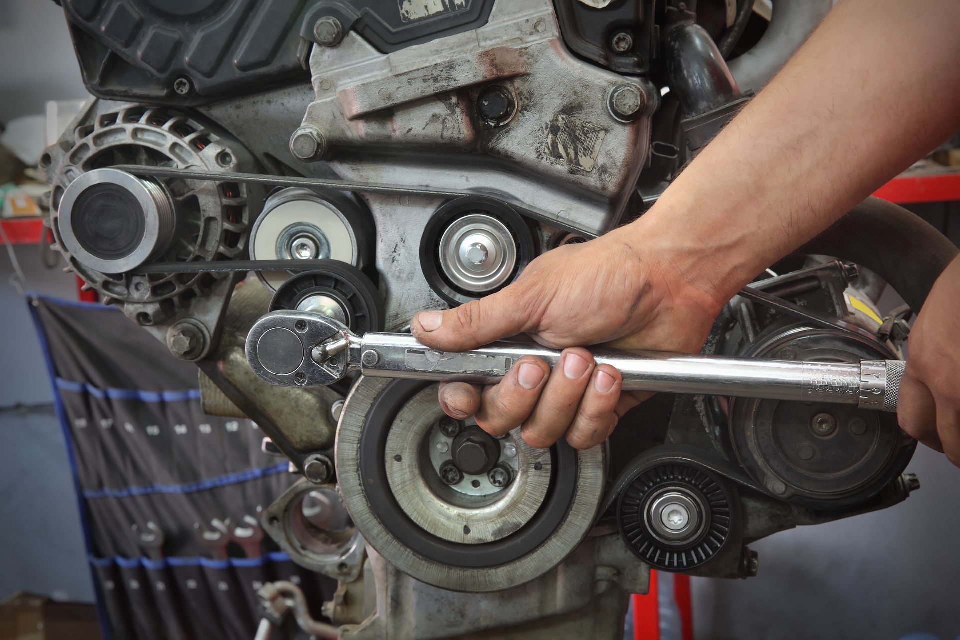 Mechanic tightening a car engine pulley with a wrench in a garage