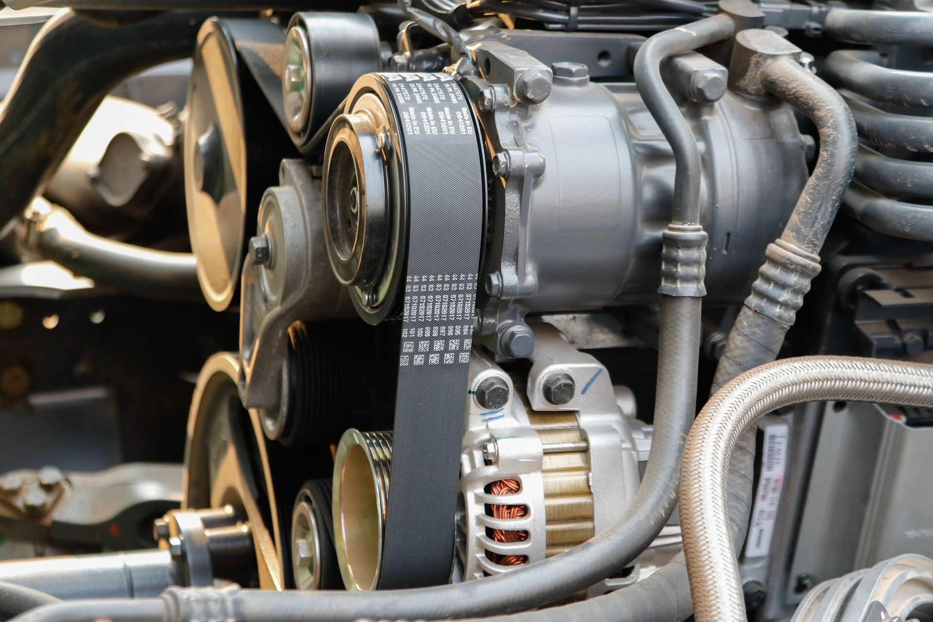 Close-up of a car engine with belts, pulleys, and metal components.