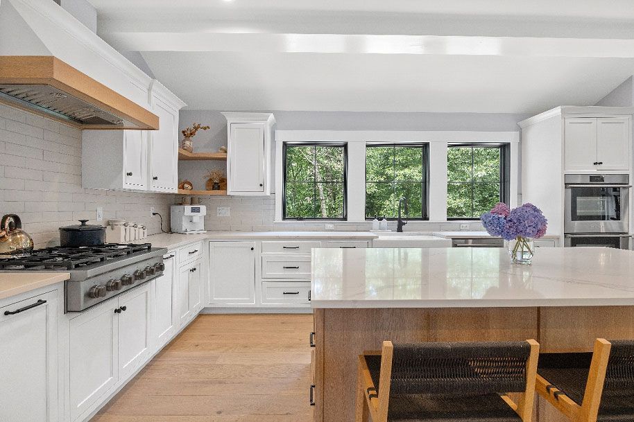 A kitchen with white cabinets, and stainless steel appliances 