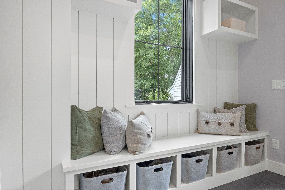 A room with a window and a bench with baskets underneath it