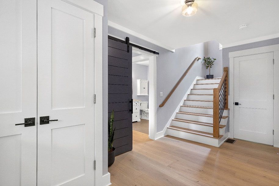 A hallway with white doors and stairs in a house