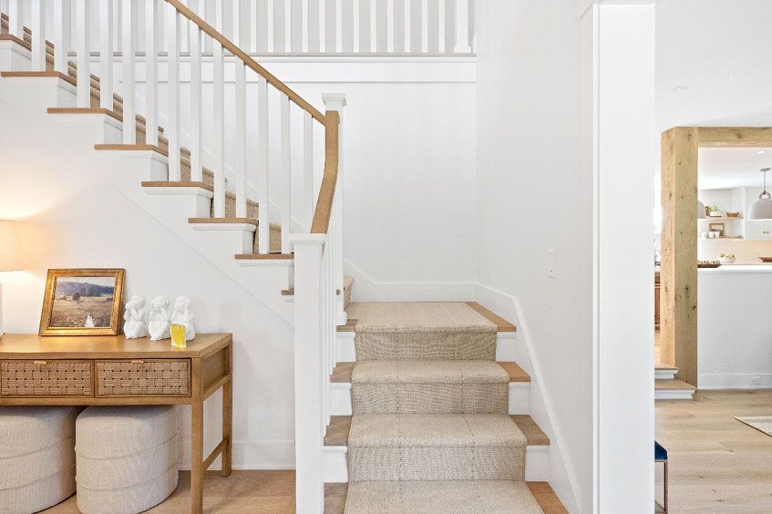 A staircase with a wooden railing and a carpeted staircase in a house