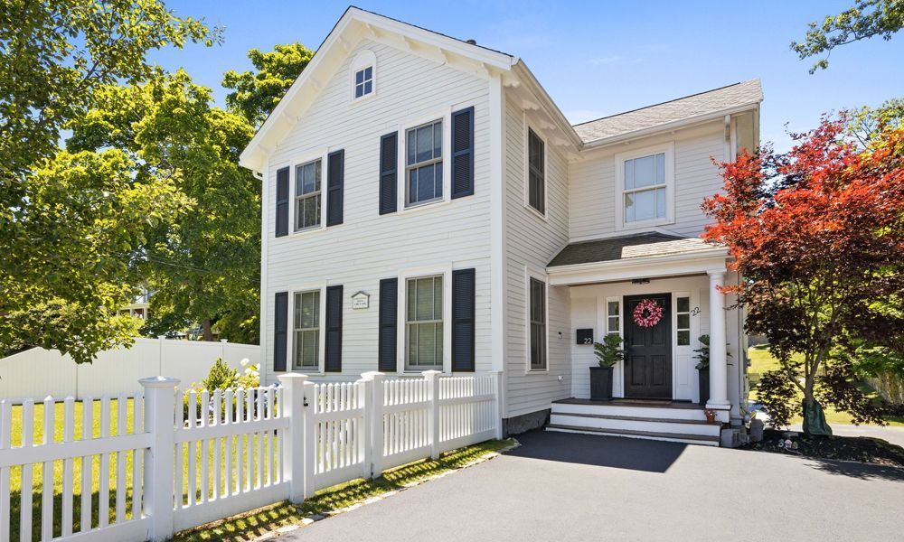A white house with black shutters and a white fence