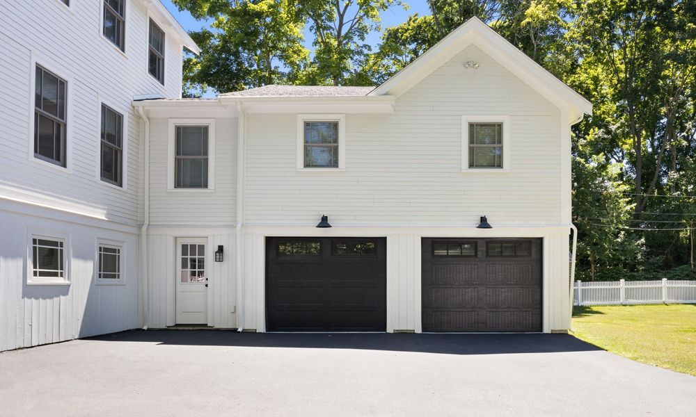 A white house with two garage doors and a driveway.