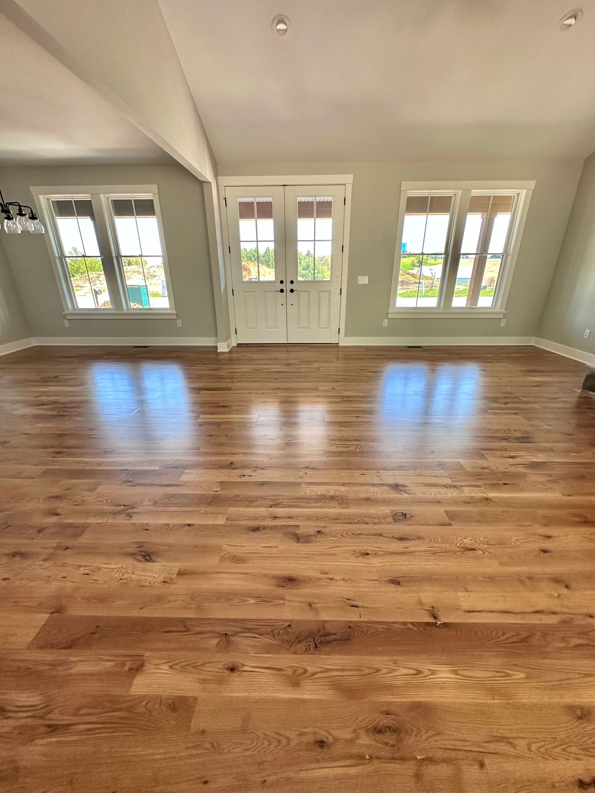 Empty room with hardwood floors and three French doors opening to a bright outdoor view