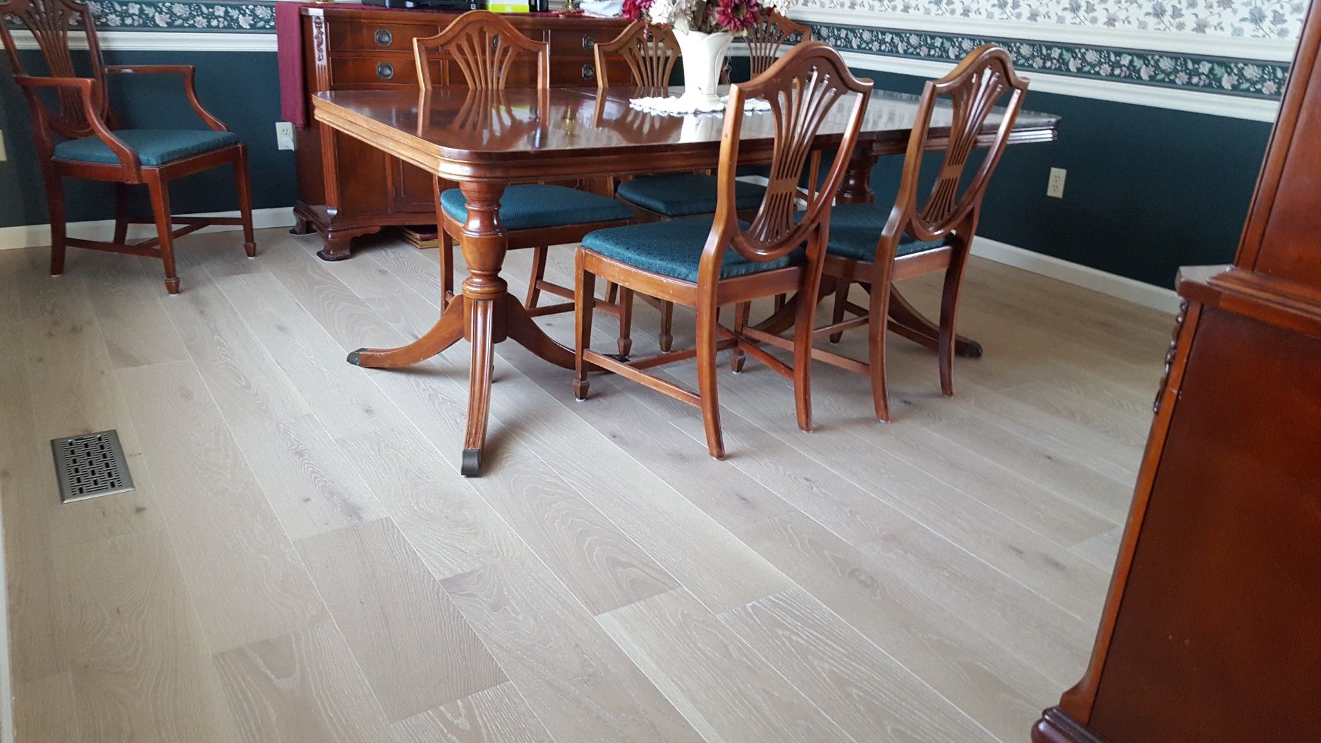 Empty dining room with wooden table and chairs on a light wood floor.