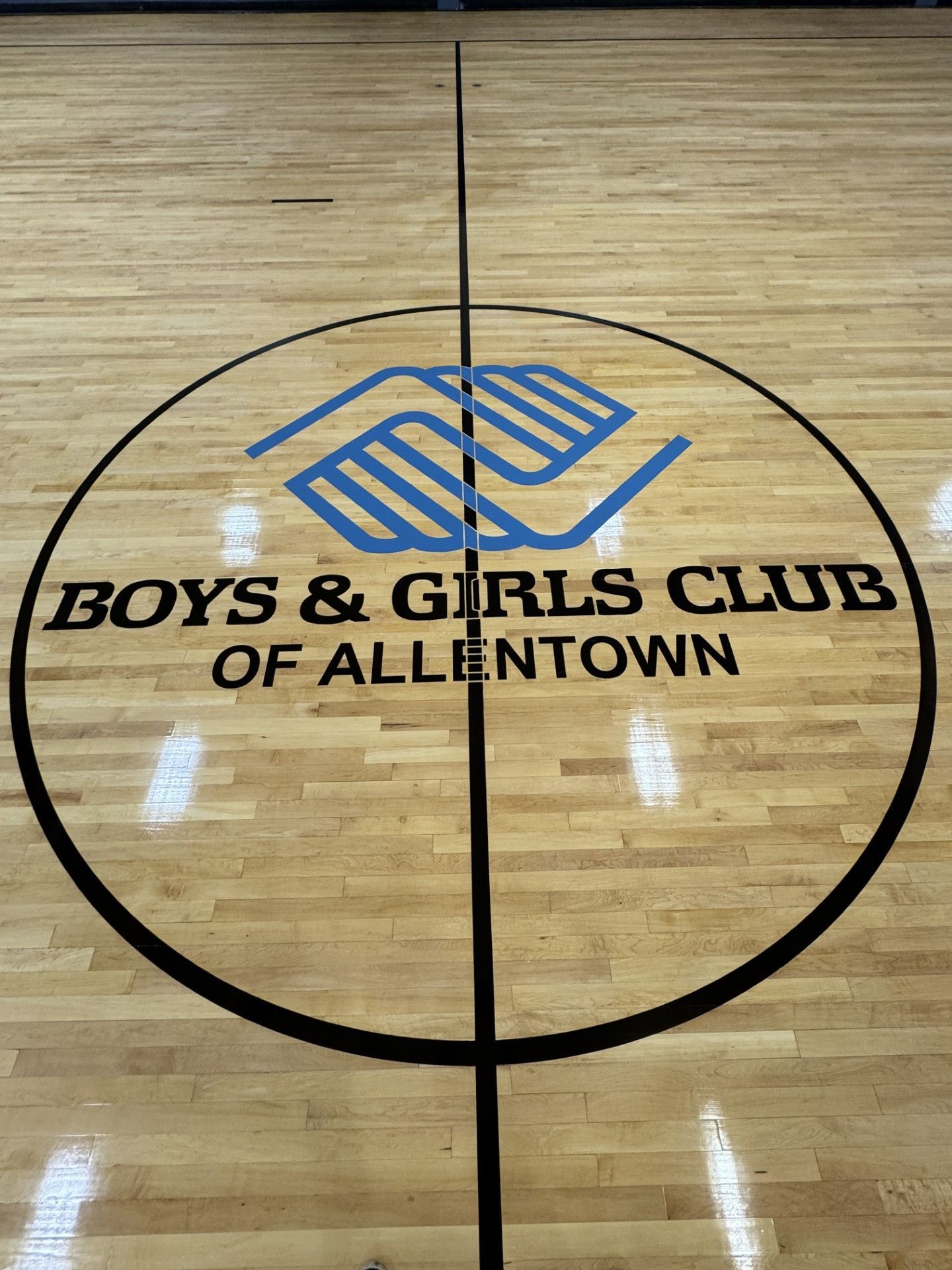 Polished oak hardwood floor in a dining room featuring a dark wood inlaid border and white wainscoting walls.