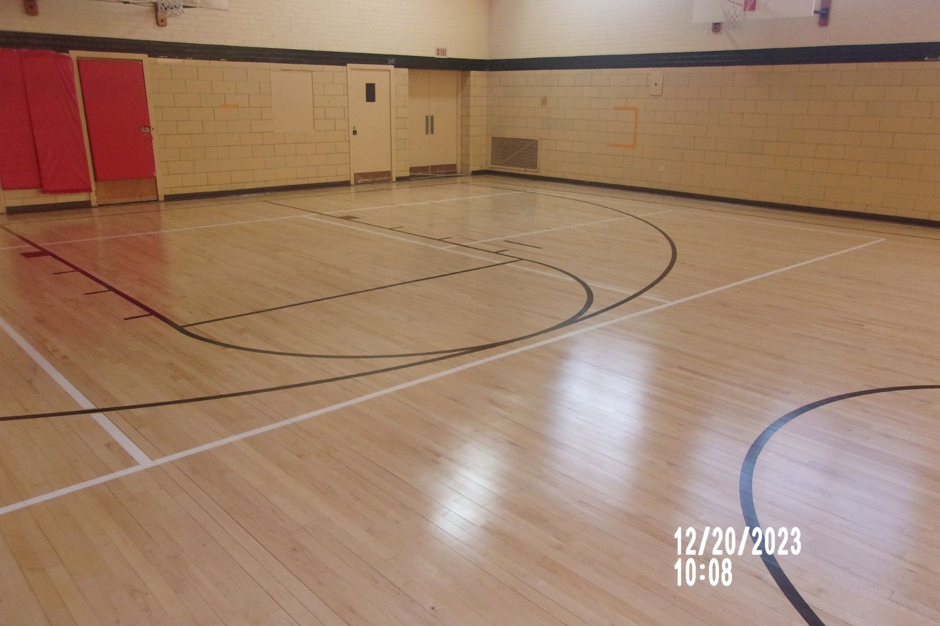 Empty indoor gym with polished wooden basketball court and beige walls