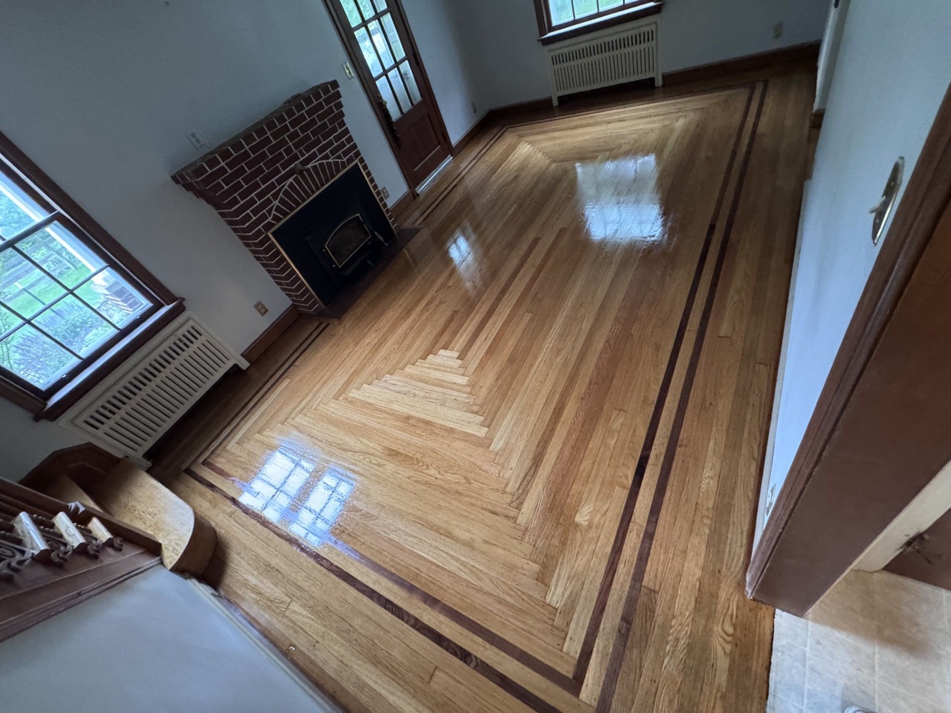 A high-angle view of a room with polished light wood flooring featuring a decorative dark wood border and mitered design.