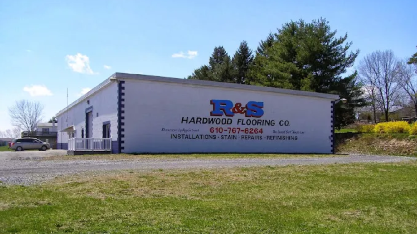 R&S Hardwood Flooring Co. storefront, white building with large blue logo on a sunny day.