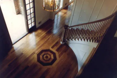 Wooden entry hall with a staircase and patterned floor inlay.