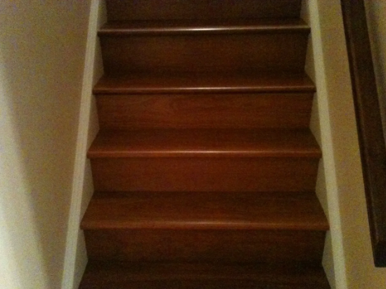 Wooden staircase with brown steps and white walls.