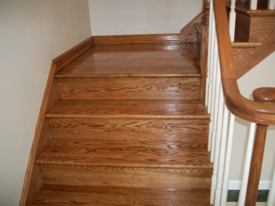 Wooden staircase with light brown treads and railing on the right, leading upwards.