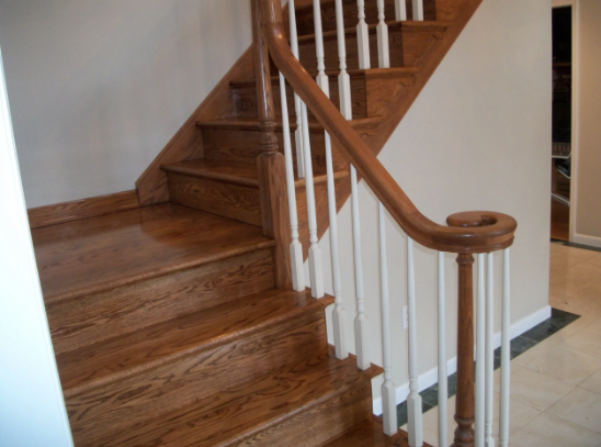Wooden staircase with white spindles, brown railing, and light-colored walls.