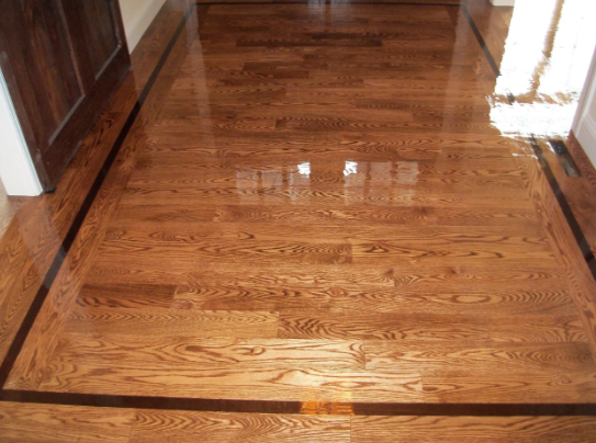 Wooden floor with a dark border reflecting light.